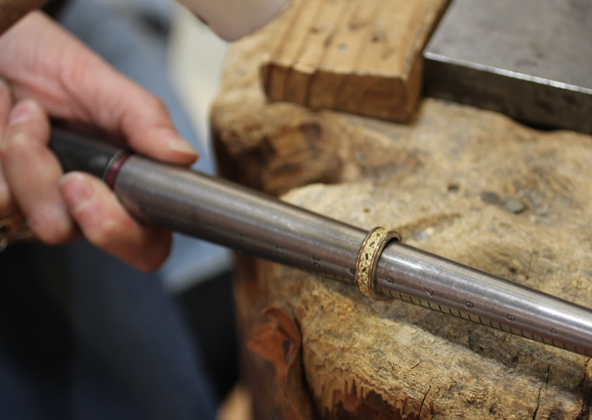 One of our jewelers uses a mandrel to check the size of a two tone wedding ring from Reflective Jewelry, before resizing this ring.